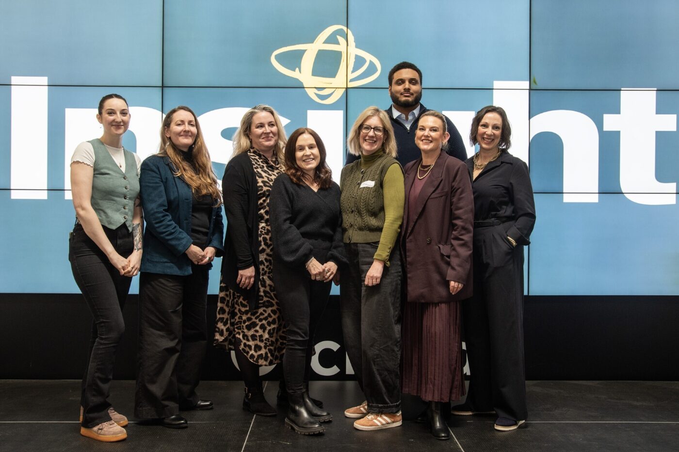 A photo of Insight HRC directors Pip Gwynn and Jemma McLean alongside the rest of the team, posing in front of a screen withe company logo